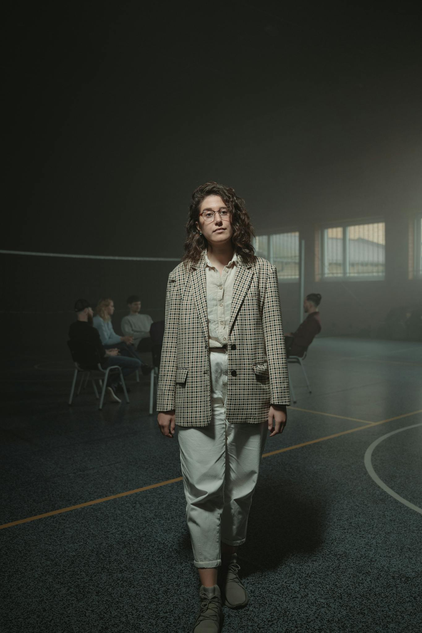 A person in front of a support group meeting in a dark indoor hall setting.