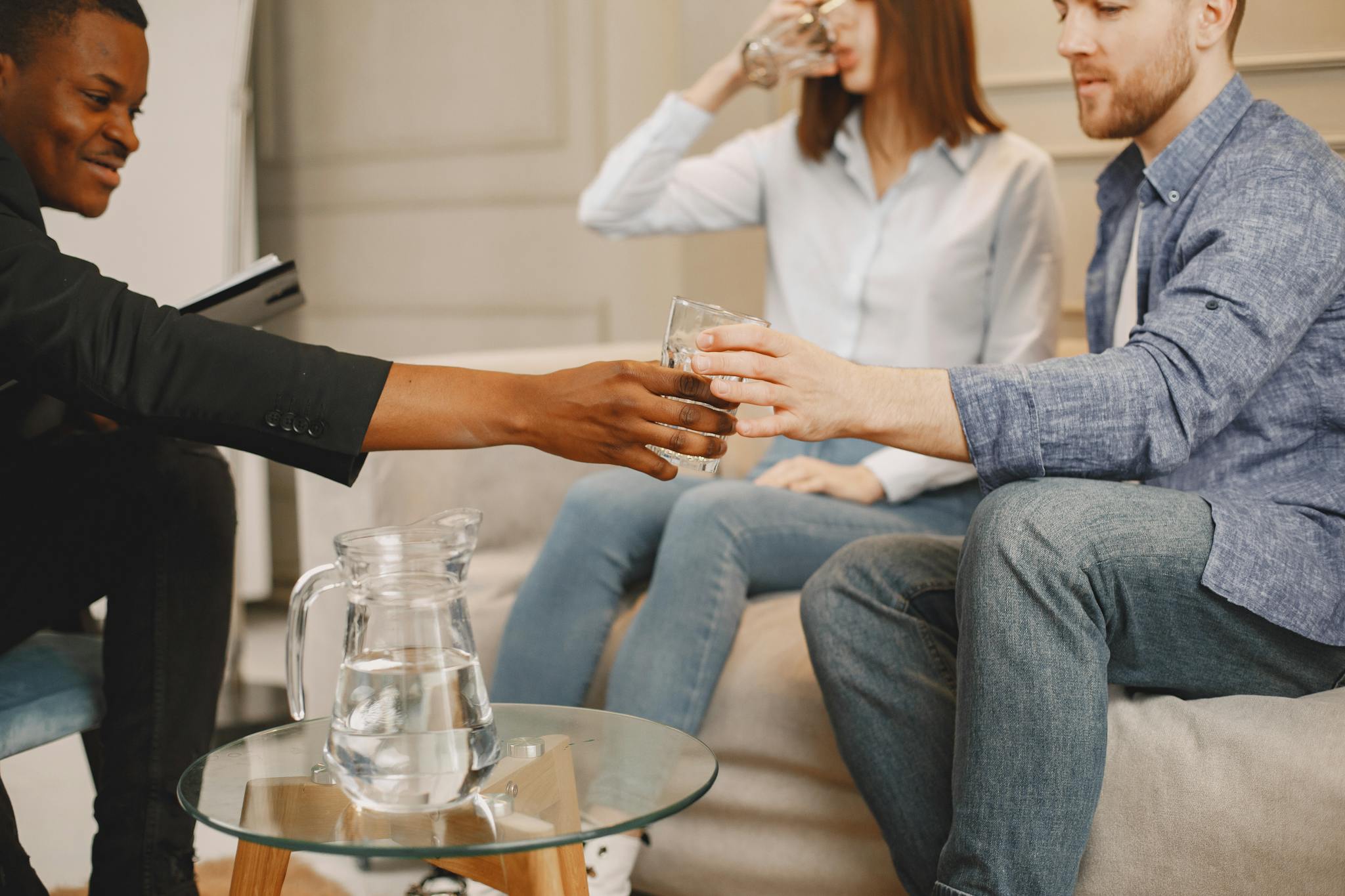 Therapist interacting with couple during counseling session indoors, sharing water.